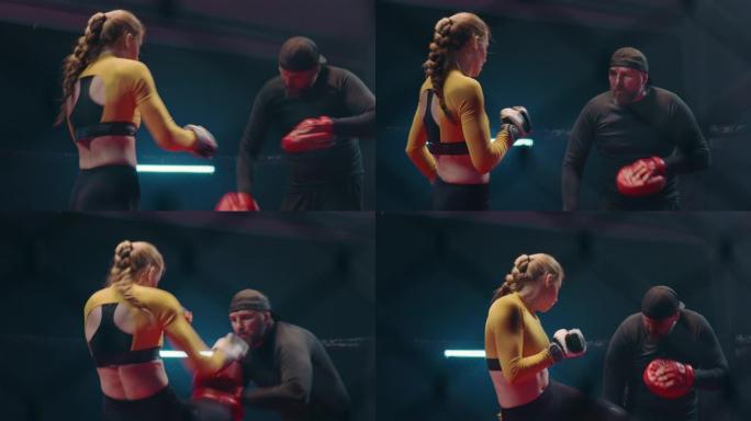 女拳击手垫与教练一起工作。背景中的第二场战斗