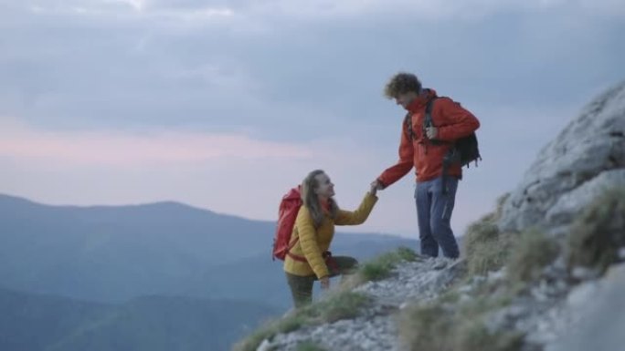 情侣一起徒步旅行伸出援手，互相帮助上山