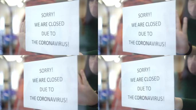 橱窗公告特写。模糊的高加索年轻店员附上通知抱歉，由于冠状病毒，我们关门了。由于新型冠状病毒肺炎大流行