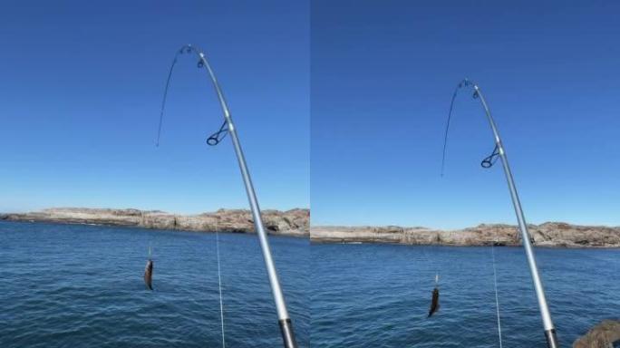 POV男子在挪威的峡湾边用钓竿在海里钓鱼