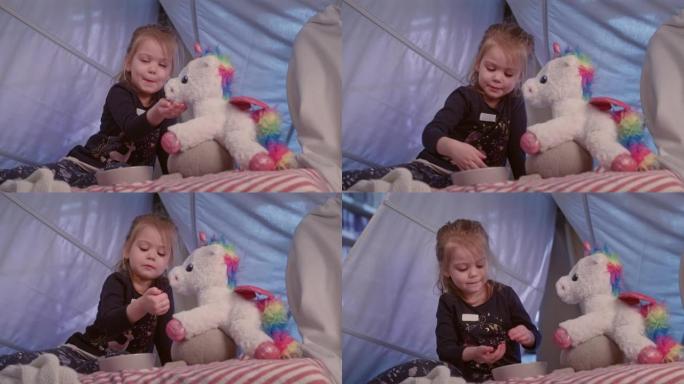可爱的小女孩在舒适的天篷床上玩她的独角兽玩具