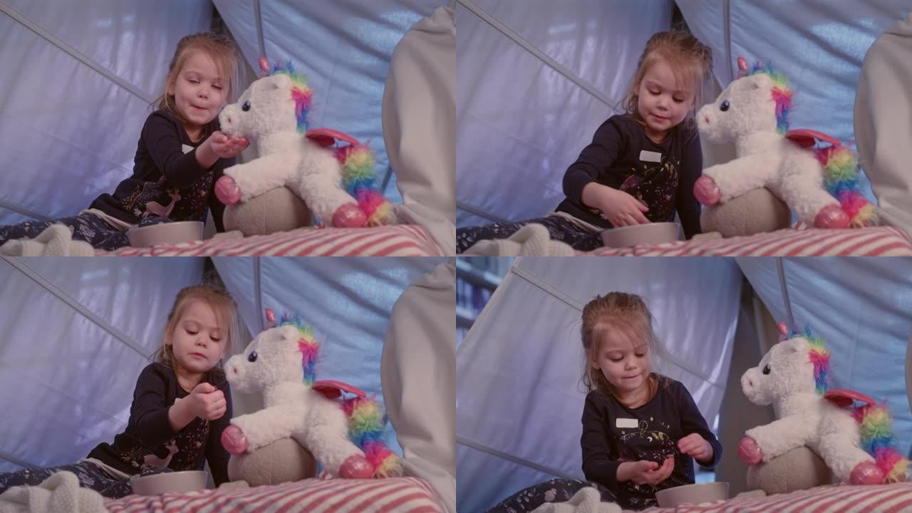 可爱的小女孩在舒适的天篷床上玩她的独角兽玩具
