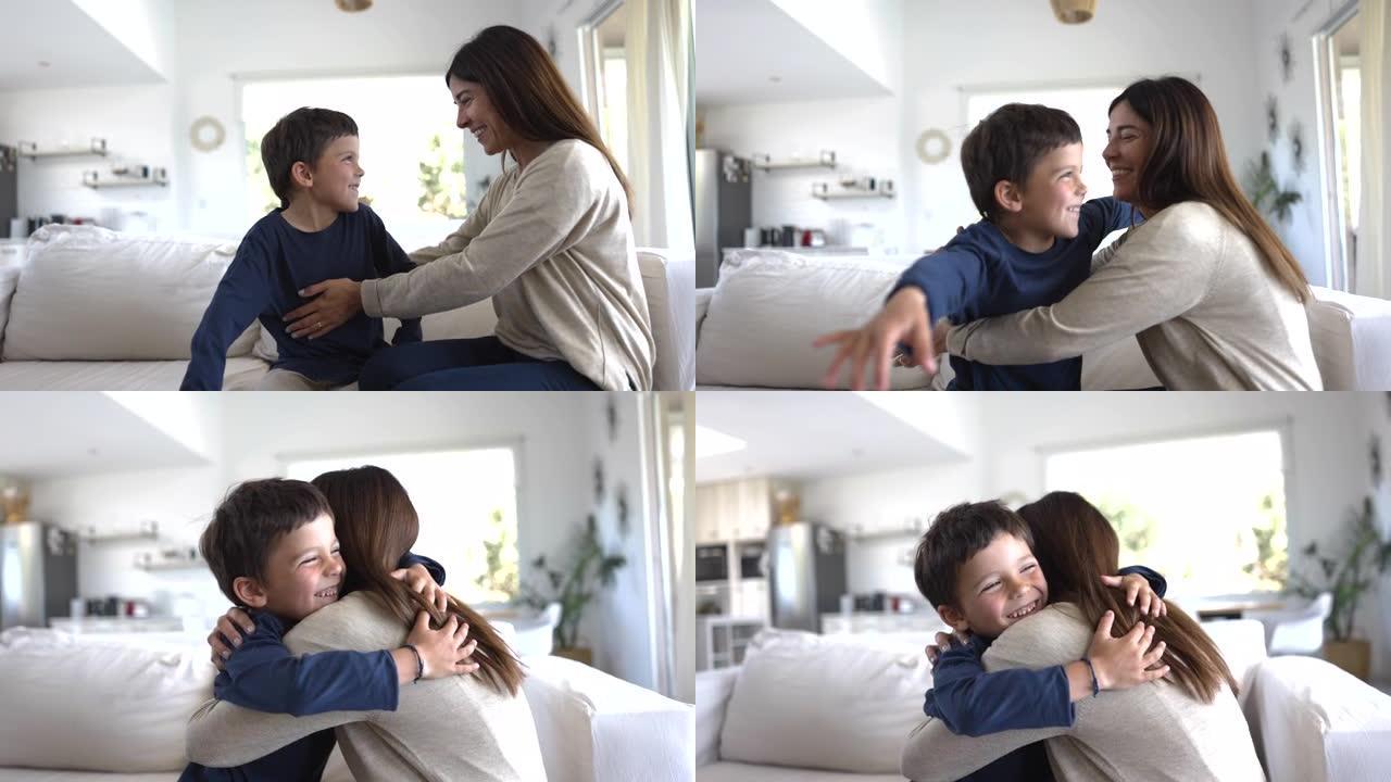 可爱的小男孩都坐在家里的沙发上，非常兴奋和慈爱地拥抱着他的妈妈