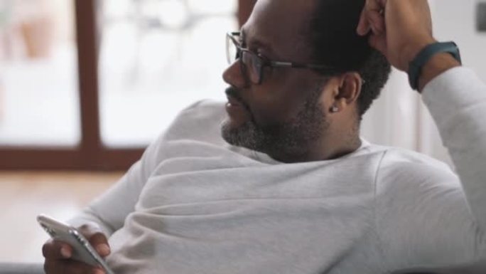 Happy African man watching TV with phone in his ha