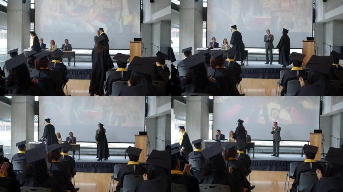毕业生在与董事会成员和大学院长握手时获得文凭的后视图