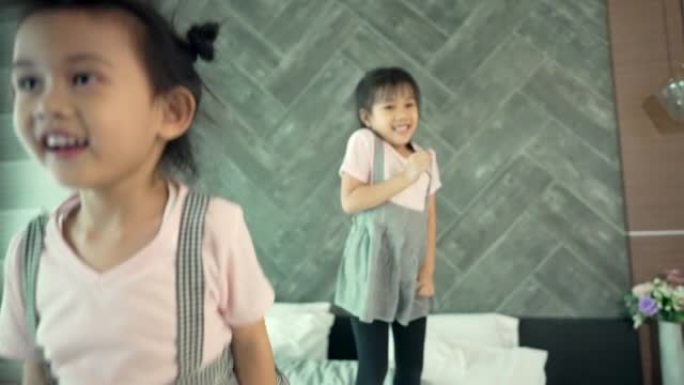 慢动作拍摄嬉戏的亚洲儿童在床上跳跃。