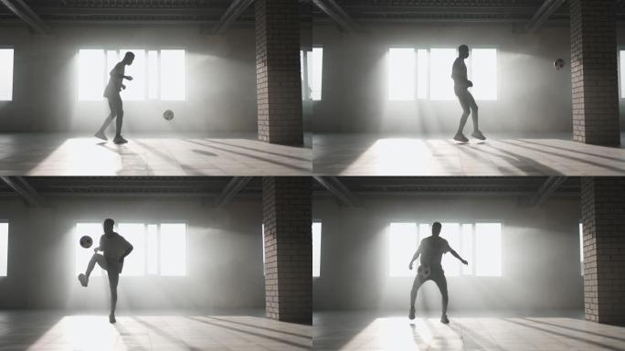一个黑人在慢动作的阳光下在地下停车场里用足球训练。玩弄球，训练传球和踢球。努力取得成功