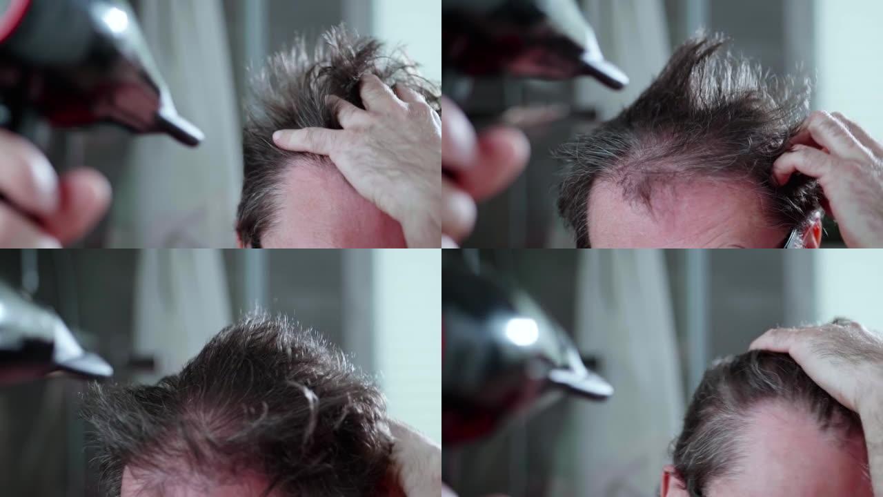 这个男人正在吹干他疯狂的头发，稀疏的头发。慢动作视频。