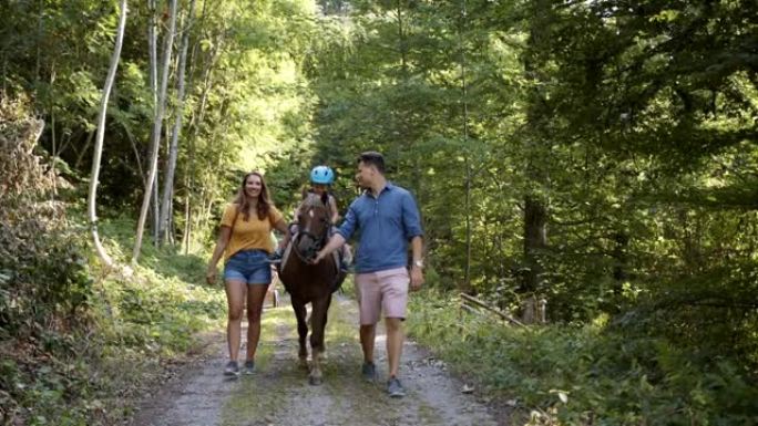 小男孩和父母在树林里骑马