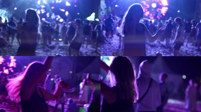 女士在露天音乐节上在沙滩上跳舞，背后有很多人