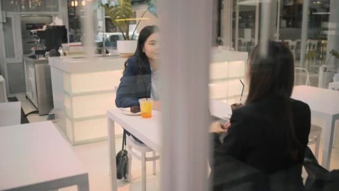 两位亚洲商界女性开会认真谈论咖啡馆外的工作。