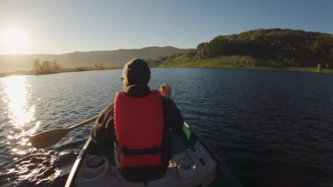 POV在湖里的独木舟上划船: 户外的夏季日落