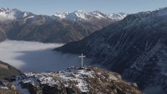 空中无人机在被山脉包围的山顶上拍摄十字架