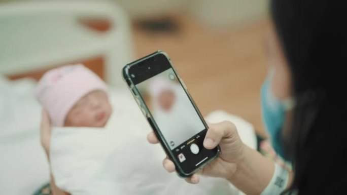 母亲用智能手机给刚出生的儿子拍照。