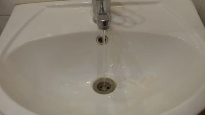 脏水从水龙头流入水槽。公寓饮用水的污染是一个问题。自来水污染。水槽水龙头生锈。选择性聚焦