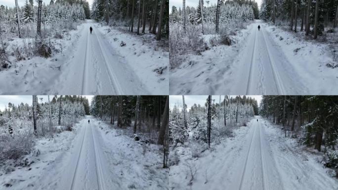 空中无人机拍摄了一名妇女在树林中沿雪道行走的镜头