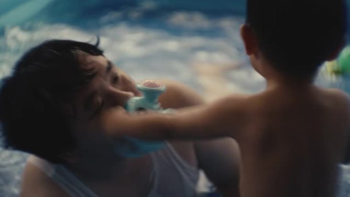 男孩和他的父亲在游泳池里玩耍