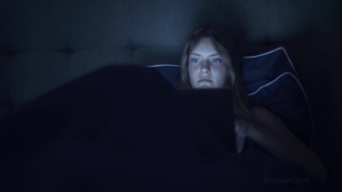 使用平板电脑设备躺在床上的女人