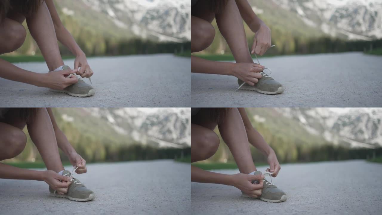 一名年轻女子在山区的碎石路上绑鞋的细节照片