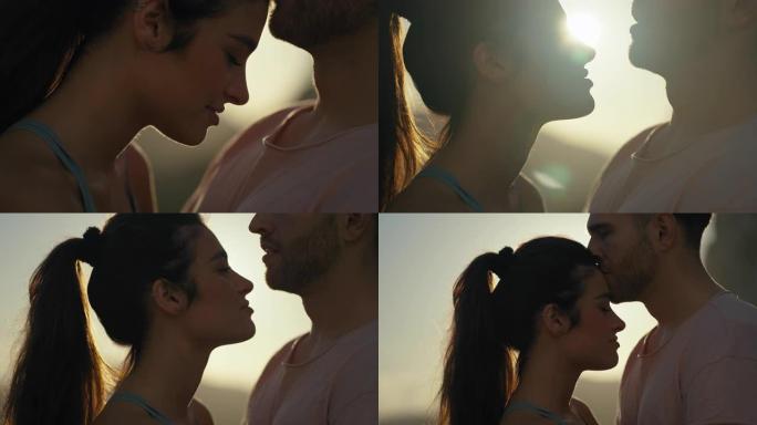 热爱游客的浪漫情侣在日落时拥抱和亲吻额头