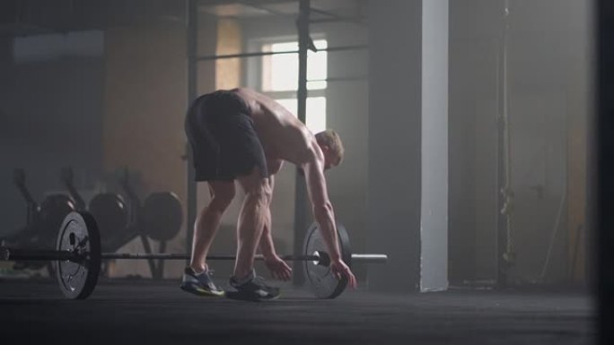 健身男子在健身房做burpee锻炼。年轻人在慢动作中做俯卧撑和跳跃运动的中等镜头。运动概念