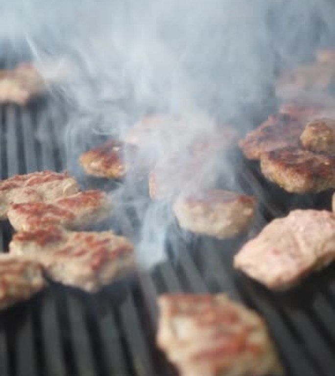 在烤架上烹饪肉类的垂直细节照片