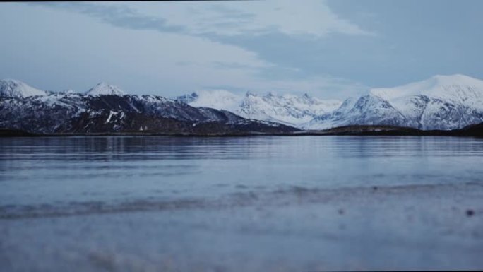 冬天特罗姆瑟海边的风景。积雪覆盖的山脉和杂草