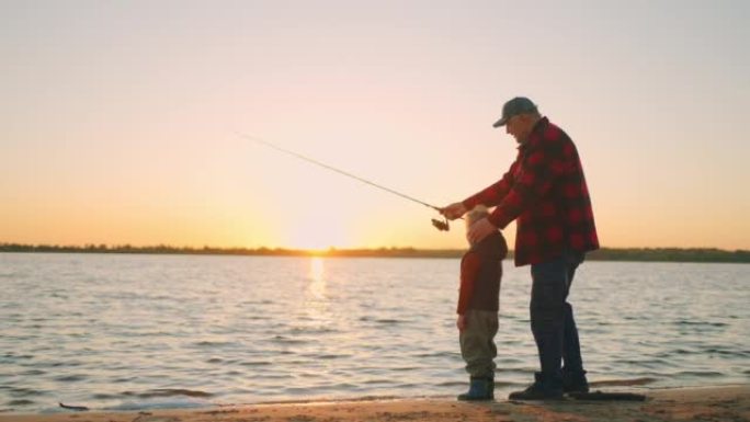 快乐的父亲和儿子在日落时在河边钓鱼，老人和小孩