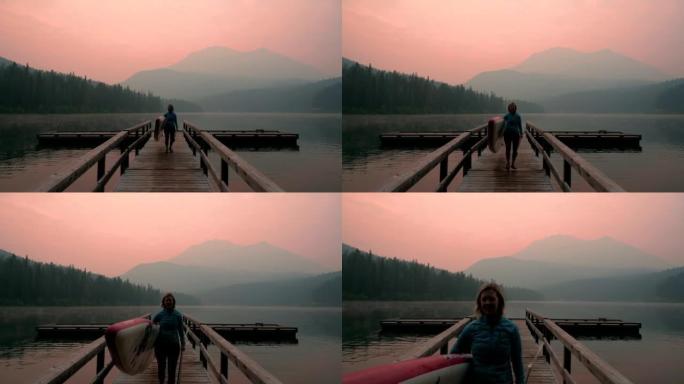 女人站在烟熏湖对面的桨板 (sup)