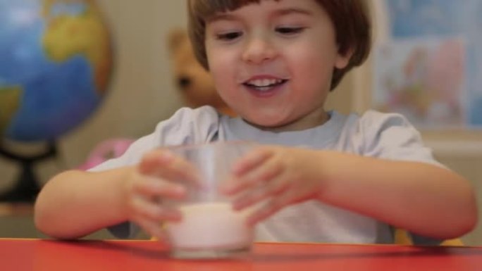 小男孩喝牛奶。健康饮食儿童吃早餐儿童梦想概念。家里的儿子男孩从玻璃杯里喝牛奶。积极的孩子微笑着吃早餐