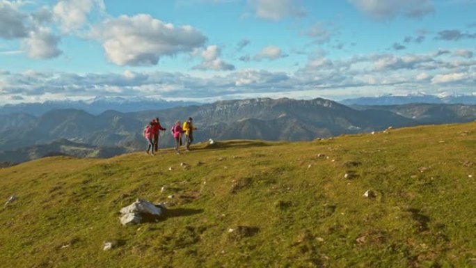 空中四名徒步旅行者在阳光下爬山在草地上