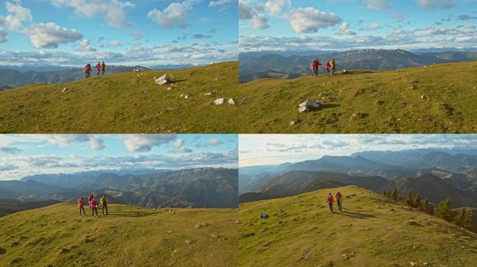 空中四名徒步旅行者在阳光下爬山在草地上