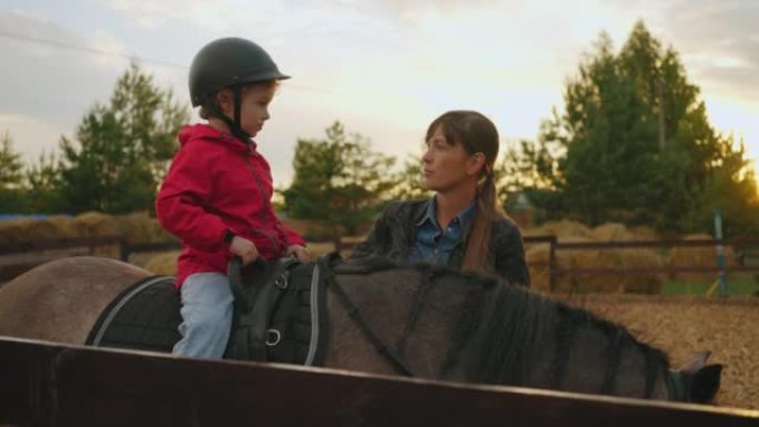 训练期间，治疗性骑马教练正在马术俱乐部与骑马的小男孩交谈
