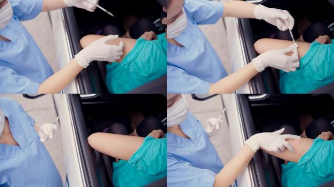 开车经过疫苗接种站，年轻的亚洲医生为那些驾驶私人汽车到站的人注射新型冠状病毒肺炎疫苗。