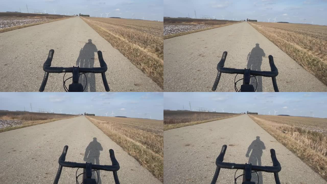 骑自行车的人在田野附近的道路上免提骑行的第一人称照片
