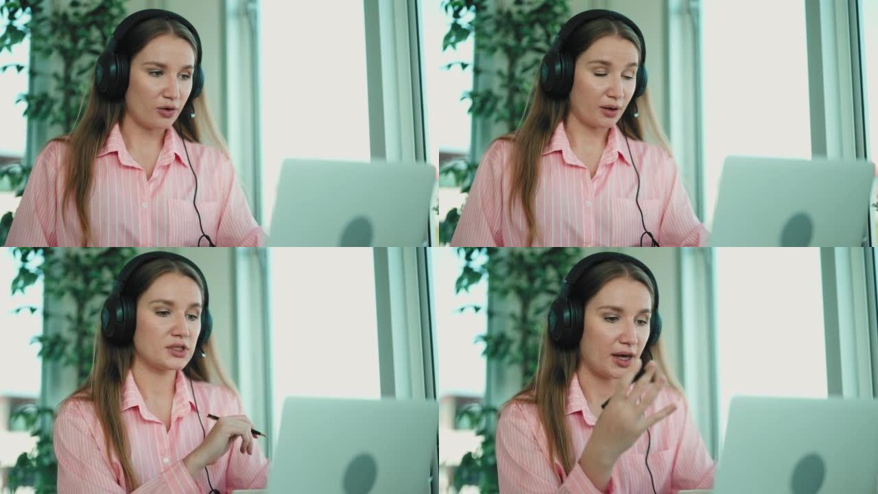 年轻迷人的女商人戴着耳机坐在办公室里使用电脑