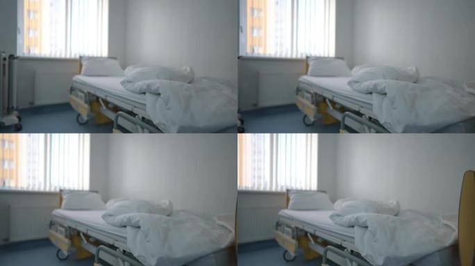 诊所病房室内配有白色干净床上用品的未整理床。在舒适的医院病房，现场摄像机沿着现代舒适的家具从左到右平
