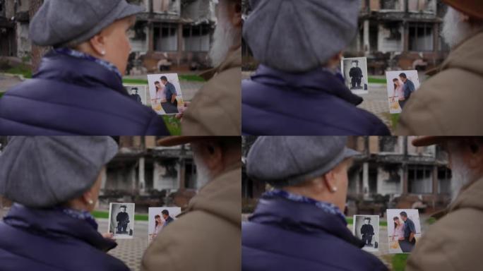 拍摄越过肩膀模糊的高级男子和妇女说话，看着旧照片站在废墟建筑的背景。乌克兰城市被炸毁的房子里绝望的夫