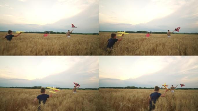 少年男孩在黑麦，风筝和玩具飞机的金色田野上奔跑，在农田里快乐的朋友或兄弟