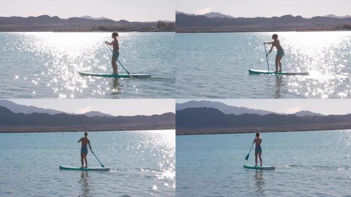 年轻女子在宁静的湖上站起来划桨 (SUP)