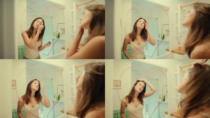 诱人的黑发女人享受她的倒影。在镜子上画口红心。早上浴室例行公事