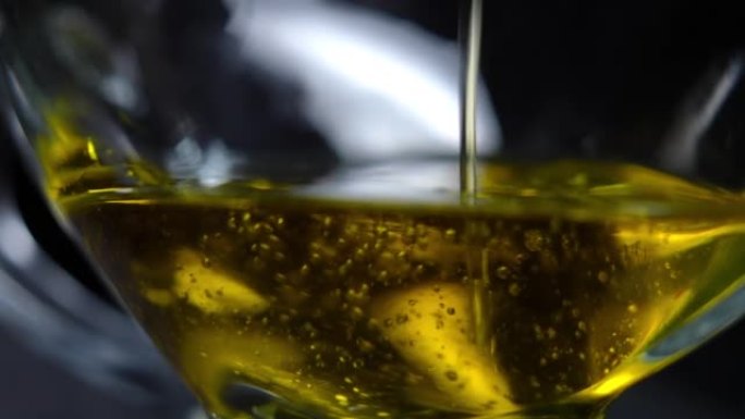 特写透明罐底，黄色金色葵花籽油慢动作浇注。黑色背景下的有机烹饪配料。