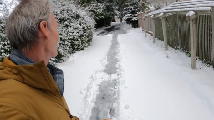 男子在漫长的车道上铲雪