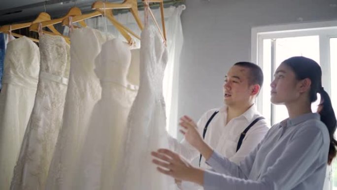 为女人选择一件白色婚纱。在婚礼工作室。