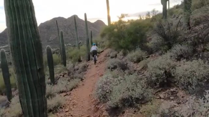 沿着沙漠小径骑自行车的女人的第一人称视角