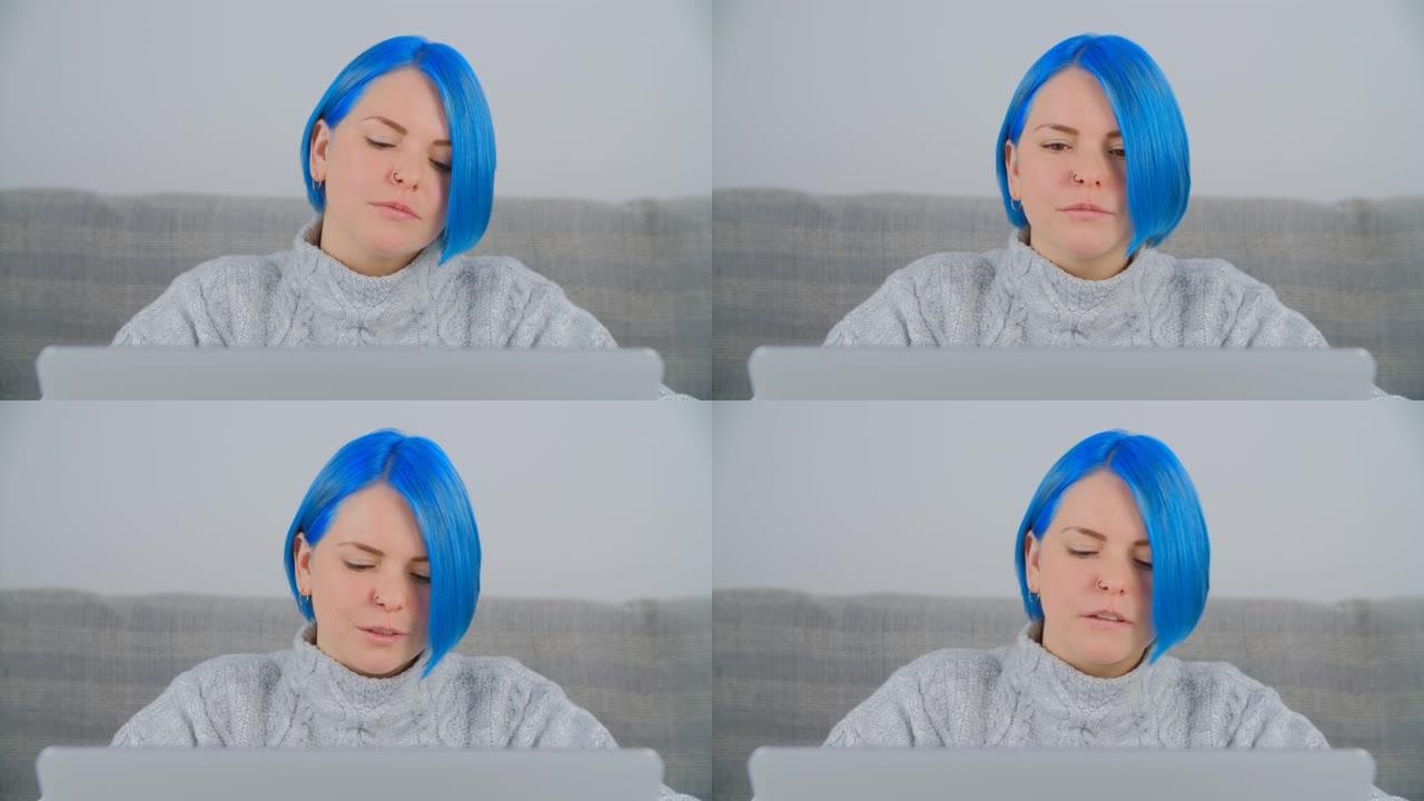 千禧一代白人妇女的肖像，鲍勃发型和染成蓝色的头发在家里的笔记本电脑上工作