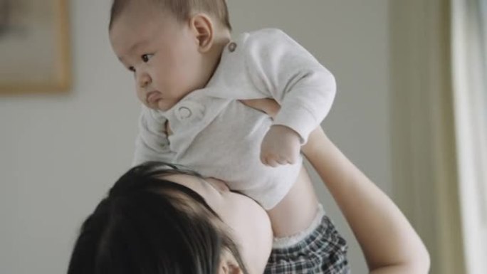 年轻的亚洲妈妈抱着并抱起她的男婴