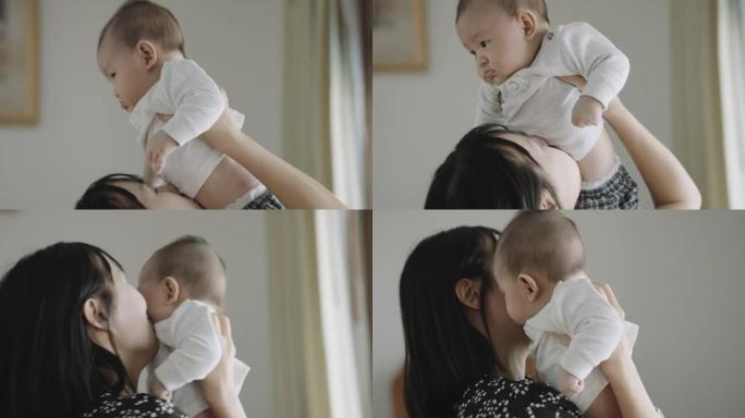 年轻的亚洲妈妈抱着并抱起她的男婴