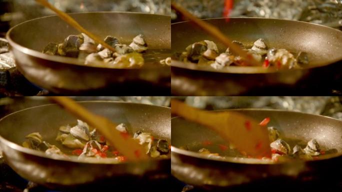 手持-海蜗牛油炸，红辣椒被添加到炙手可热的平底锅中