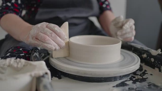 在陶工轮上工作的大师的手的特写镜头，以慢动作制造粘土和陶瓷罐和板